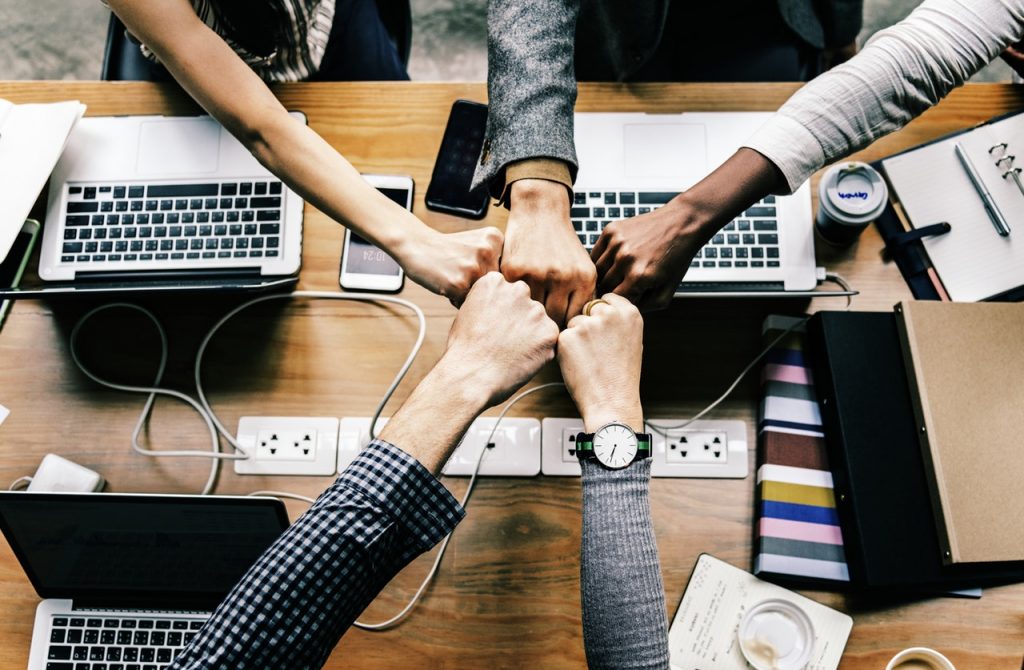 Close up top view of young business people putting their hands together